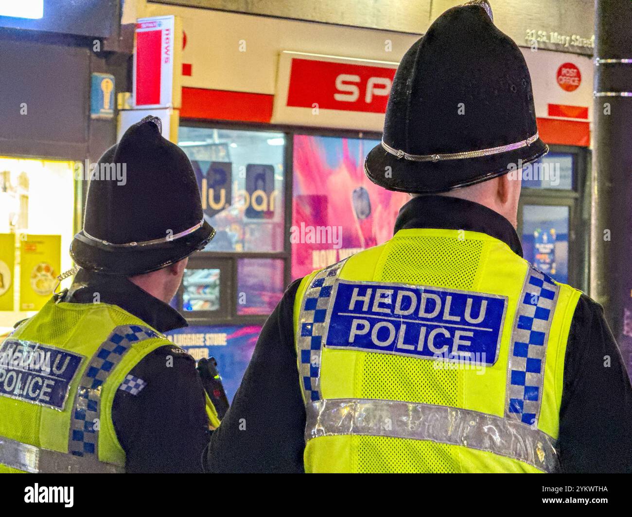 Cardiff, Wales, UK - 17 November 2024: Rear view of officers of South Wales Police on duty in the city centre at night - Smartphone Captured Stock Image