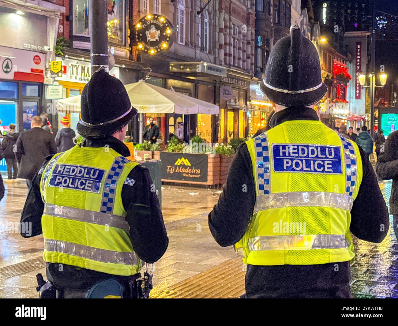 Cardiff, Wales, UK - 17 November 2024: Rear view of officers of South Wales Police on duty in the city centre at night - Smartphone Captured Stock Image