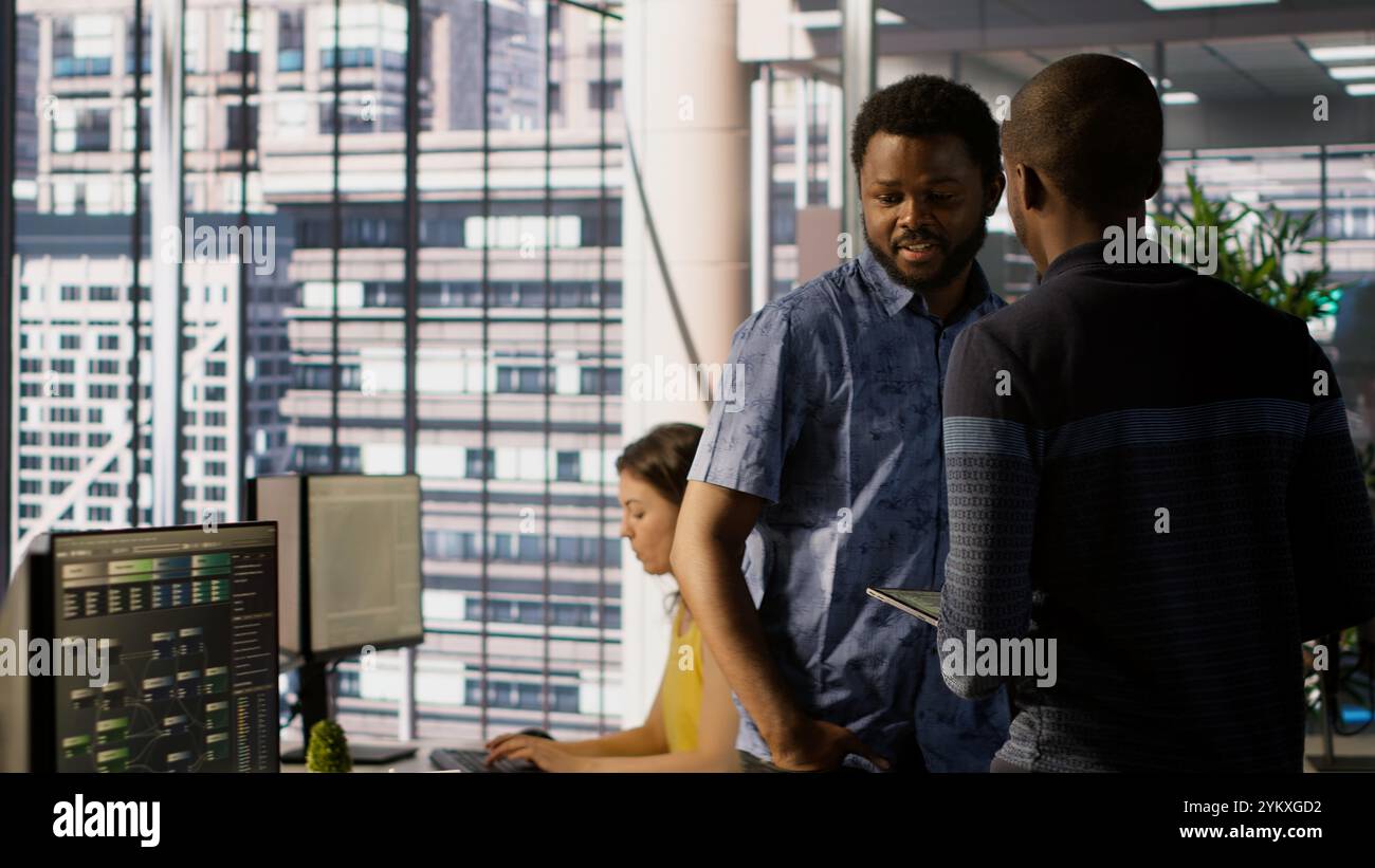 Managers evaluating work done by computer scientists in workspace doing software debugging. Management executives walking in office with tablet, checking code fixed by employees, camera A Stock Photo