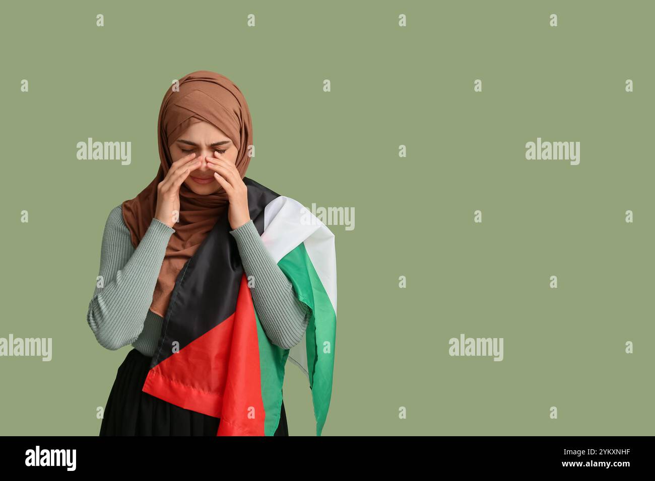 Young sad Muslim woman with Palestine flag crying on green background ...