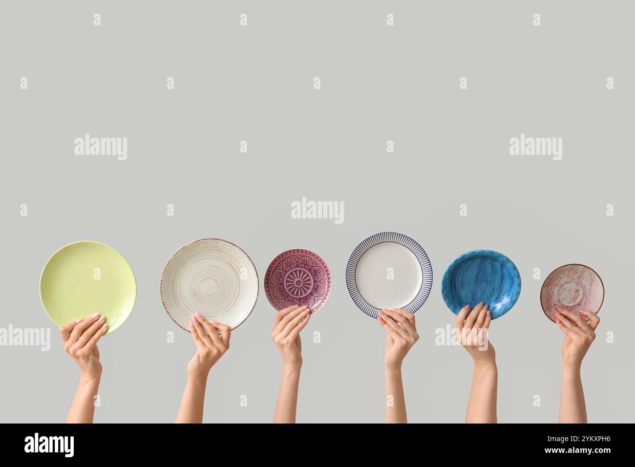 Hands holding empty plates on light background Stock Photo