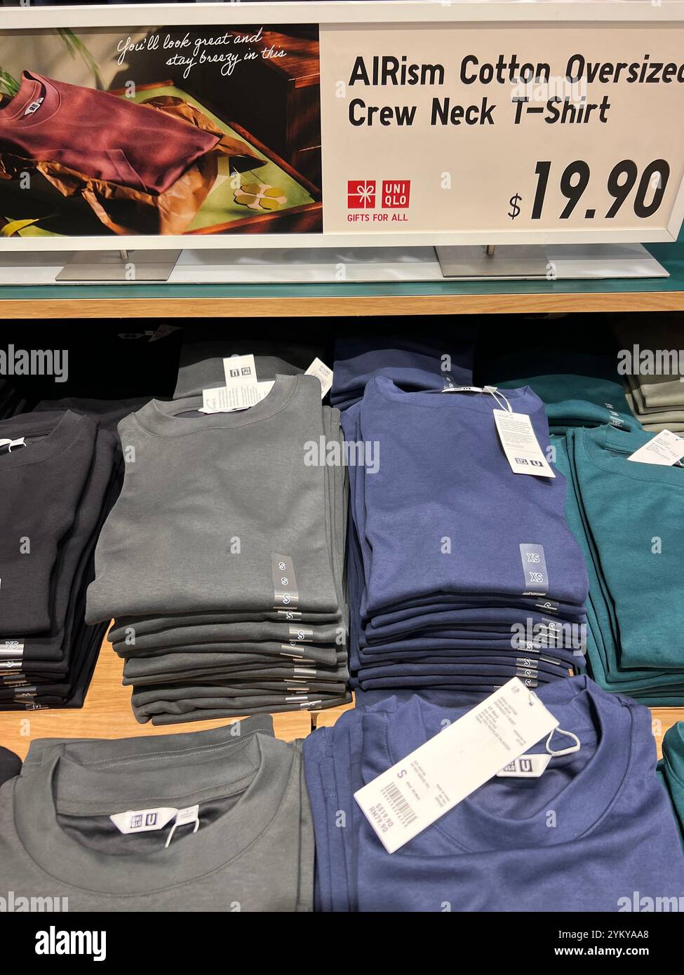 Vertical view, Uniqlo display AIRism cotton oversized crew neck t shirt in varies colours, price for $19.90. Singapore. - Smartphone Captured Stock Image
