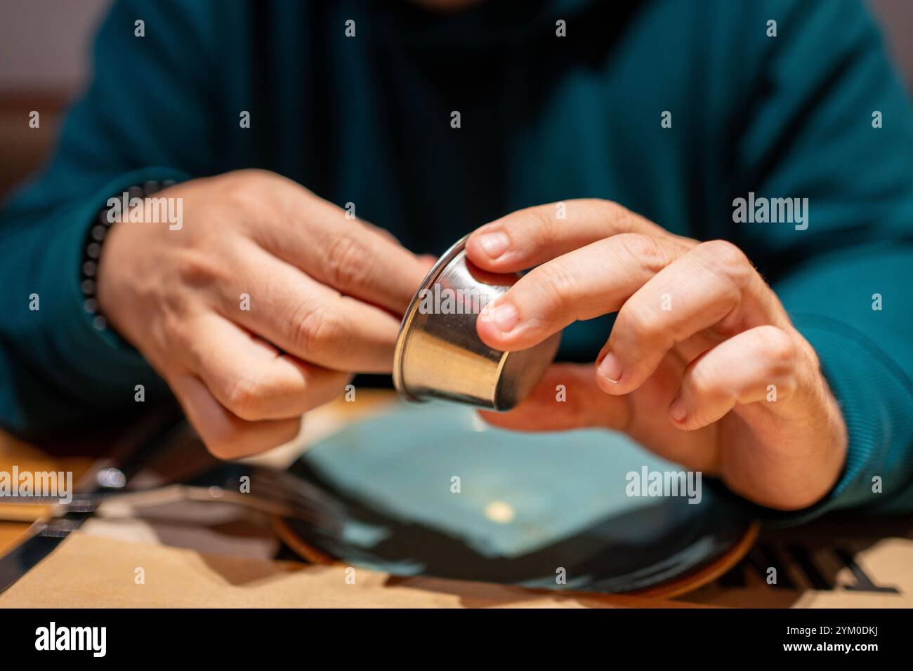 Restaurant patron holding a small metal cup, likely containing a sauce or condiment Stock Photo