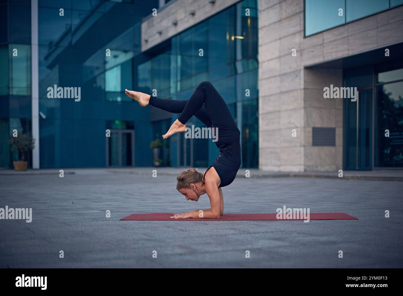 Practicing advanced yoga poses outdoors in an urban setting during the evening Stock Photo