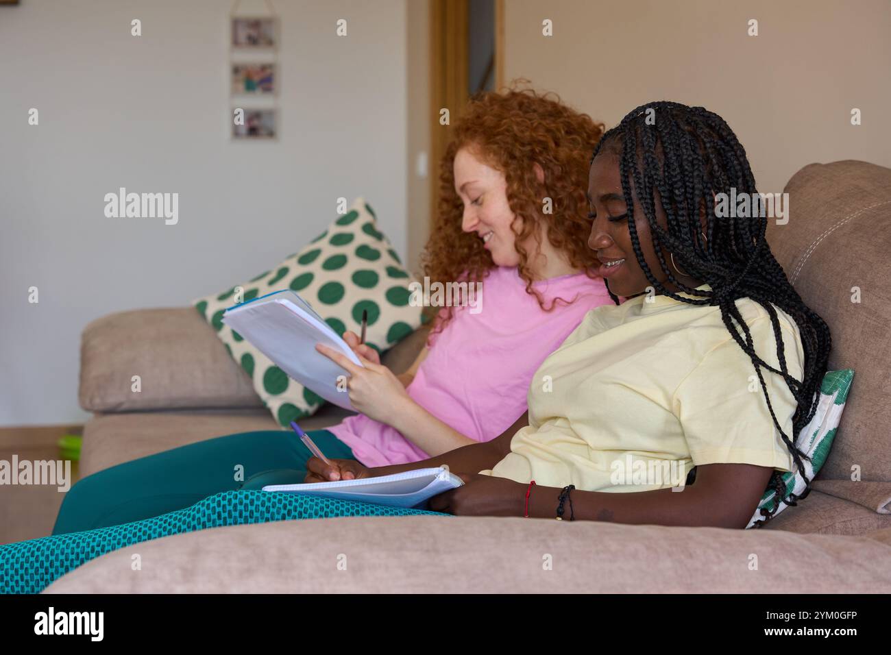 Students working on homework together on sofa at home Stock Photo