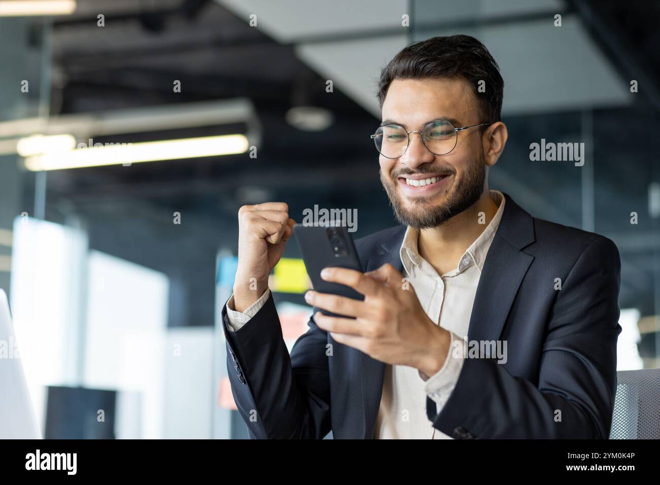 Smiling businessman celebrates success checking smartphone. Happy ...