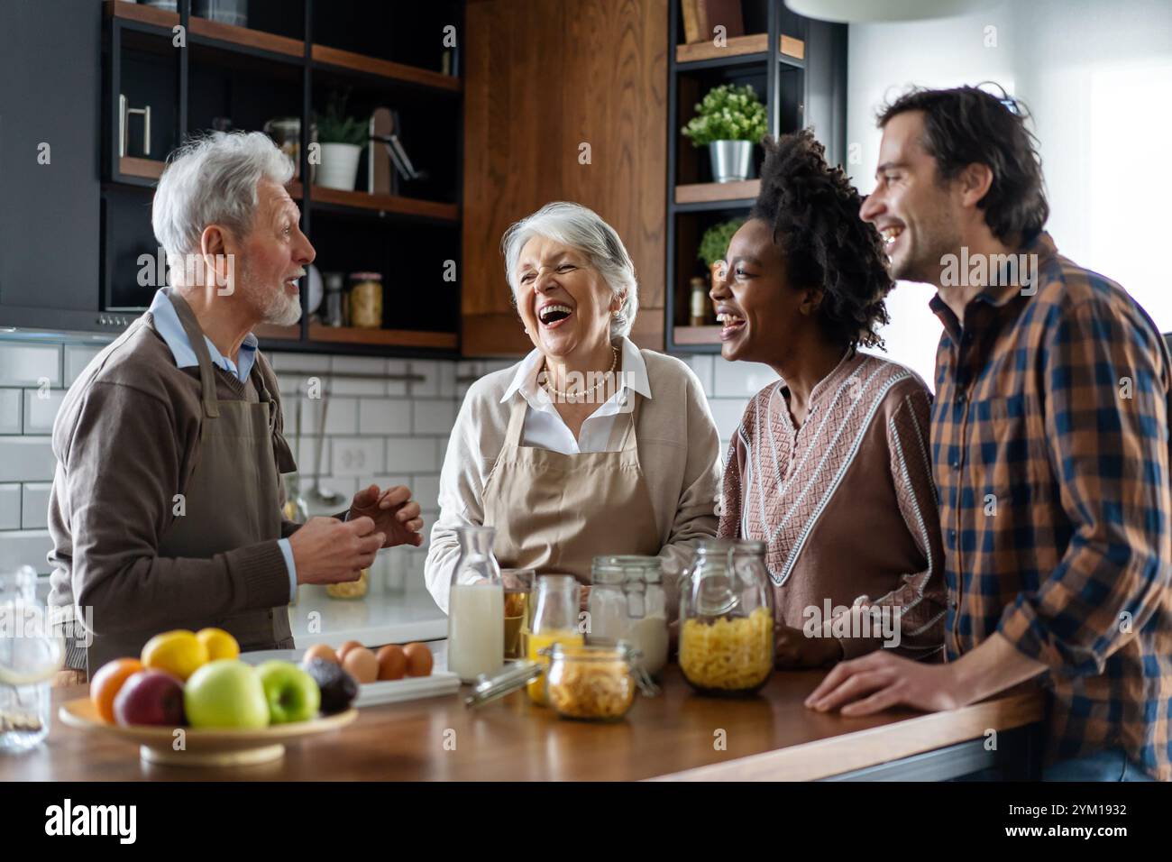Multi generation multiethnic family having fun, talking around a festive kitchen table. Stock Photo