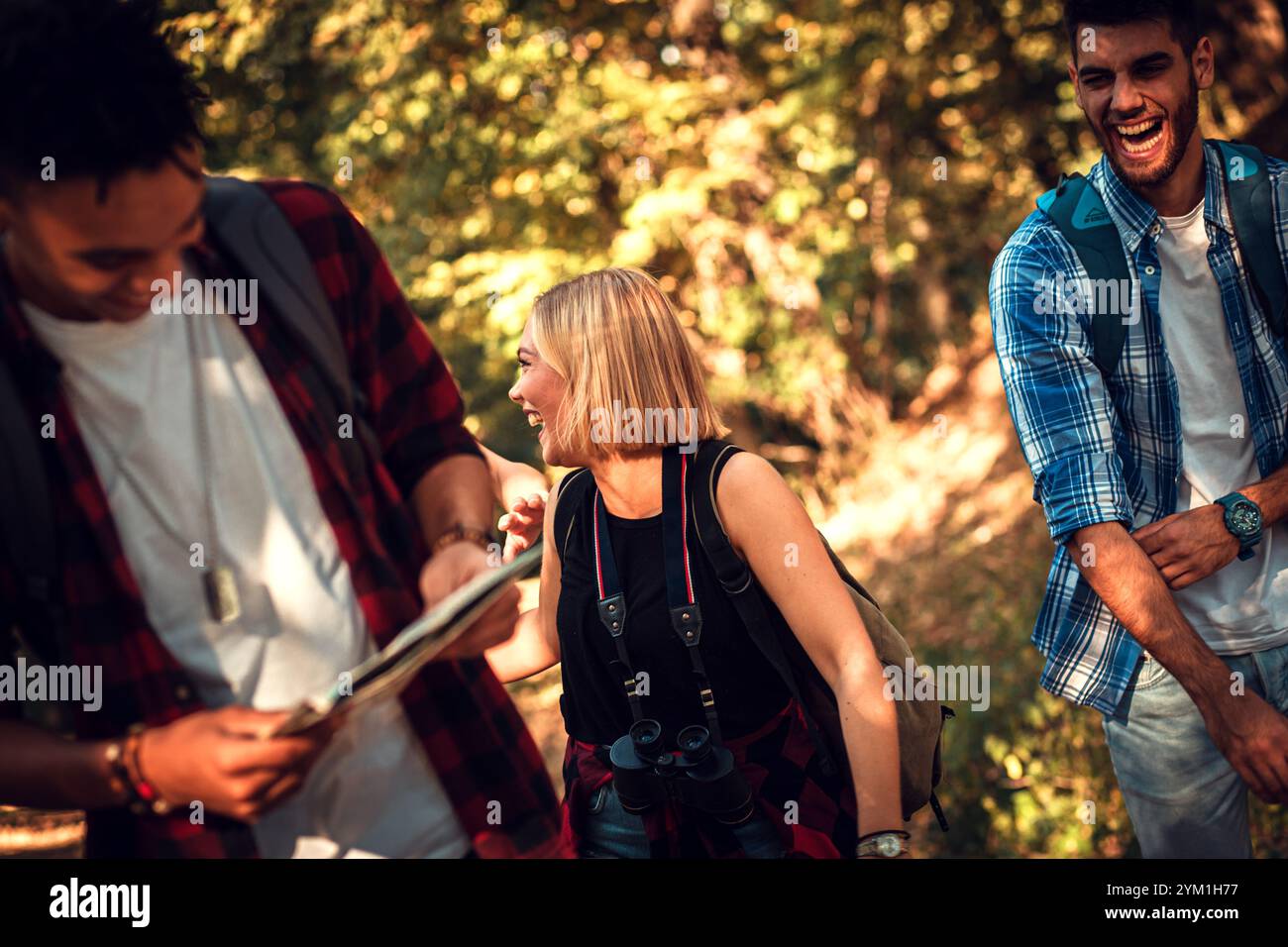 Group of four friends having fun hiking through forest together. Stock Photo