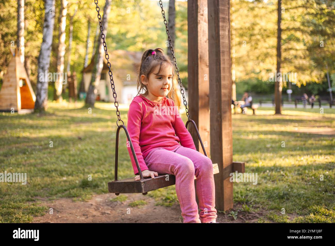 Cute smiling girl on a swing in the playground Stock Photo - Alamy