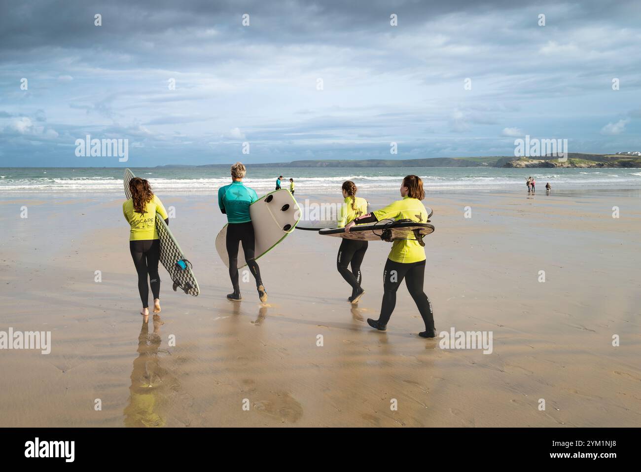 A surfing instructor from the Escape Surf School with his surfing novices learners at the start of a surfing lesson on Towan Beach in Newquay in Cornw Stock Photo