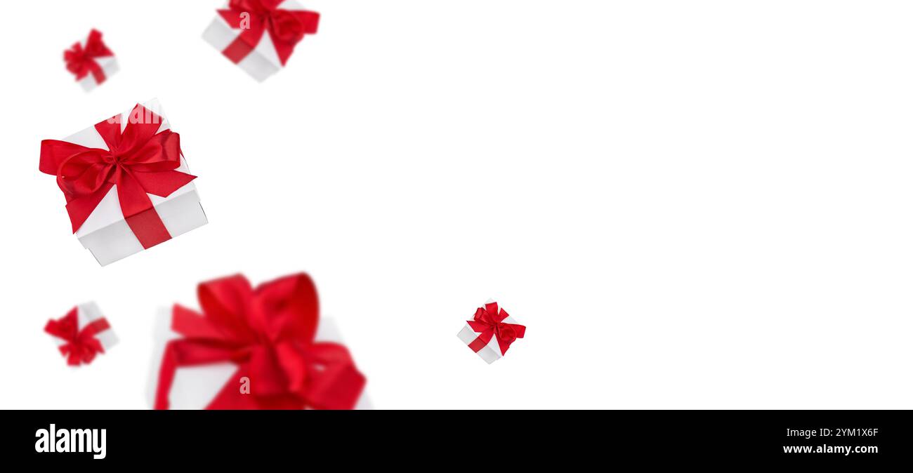 Flying Christmas white gift boxes with red bows from satin ribbon isolated with clipping path. Element for design. Banner with copy space for text. Stock Photo