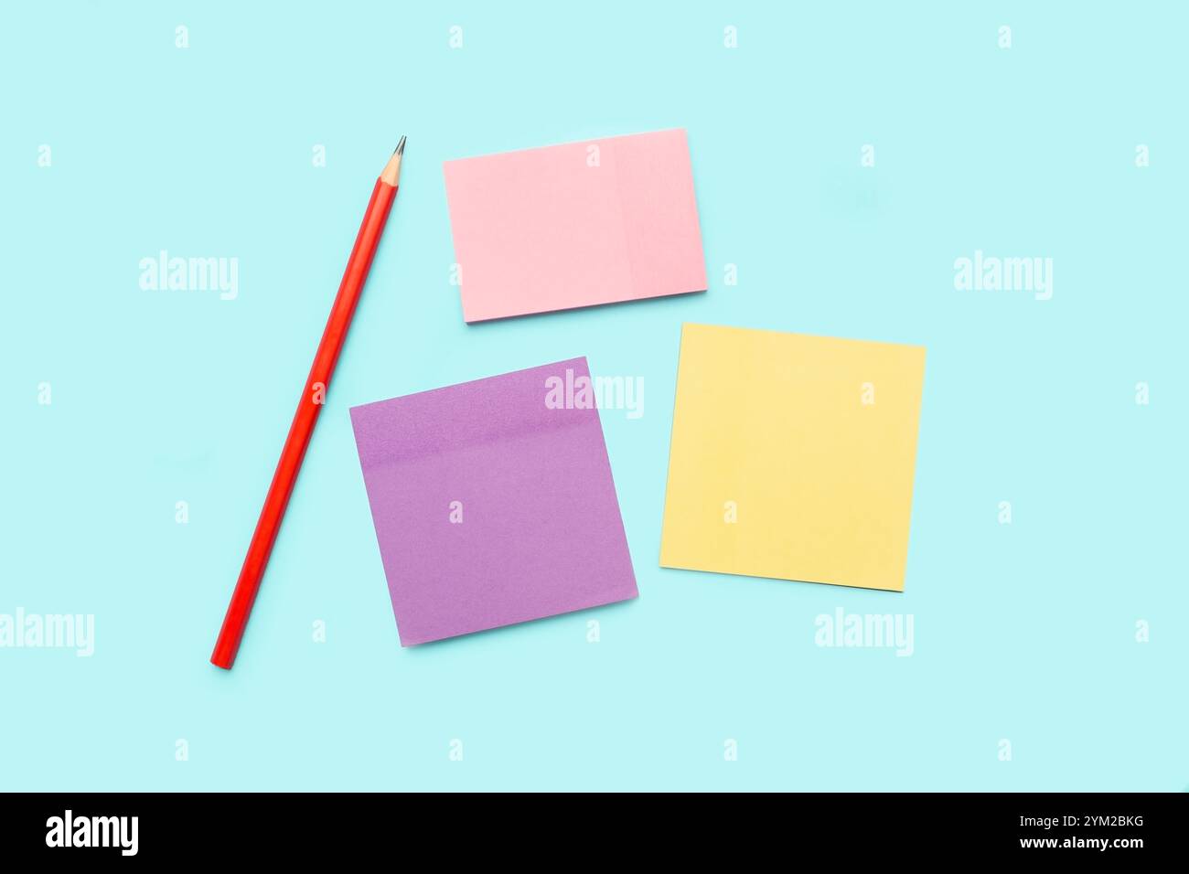 A pencil and colored paper notes on a light blue background Stock Photo