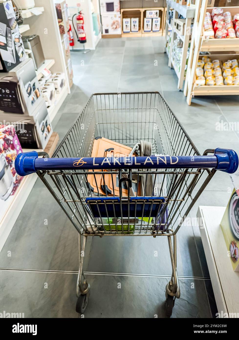 Selective focus on handle of shopping trolley of the Lakeland store, the name is clearly visible.  Displays of goods visible in the blurred background - Smartphone Captured Stock Image
