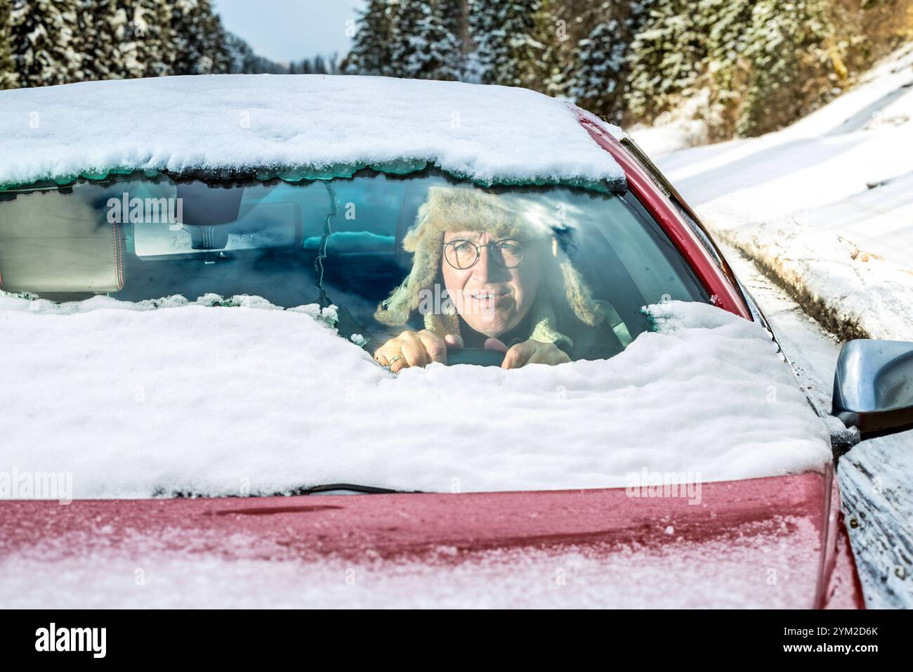 Wintereinbruch, Autofahrer hat schlechte Sicht, weil er die Windschutzscheibe nur halb vom Schnee befreit hat, München, 20. November 2024 Deutschland, München, November 2024, Wintereinbruch, Autofahrer hat Windschutzscheibe nur halb vom Schnee befreit, Windschutzscheibe und Autodach teils schneebedeckt, schlechte Sicht, tiefstehende Sonne blendet, Glättegefahr, Wintereinbruch, Winterwetter, Winter, Hintergrund verändert, Bayern, *** Onset of winter, car driver has poor visibility because he has only half cleared the windshield of snow, Munich, November 20, 2024 Germany, Munich, November 2024, Stock Photo