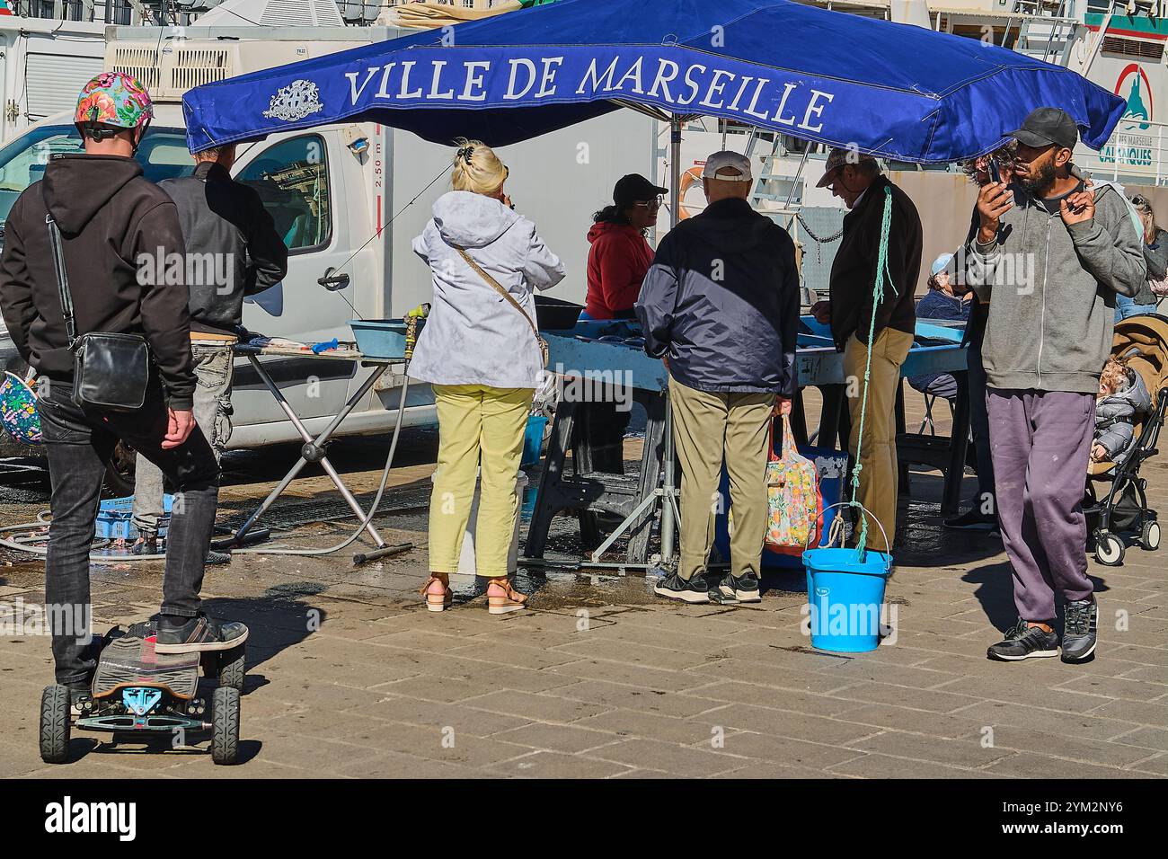 Marseille. France  - November 20,2024: A fish vendor at the Old Port of Marseille, handling fresh seafood at her stall. Surrounded by historic buildin Stock Photo