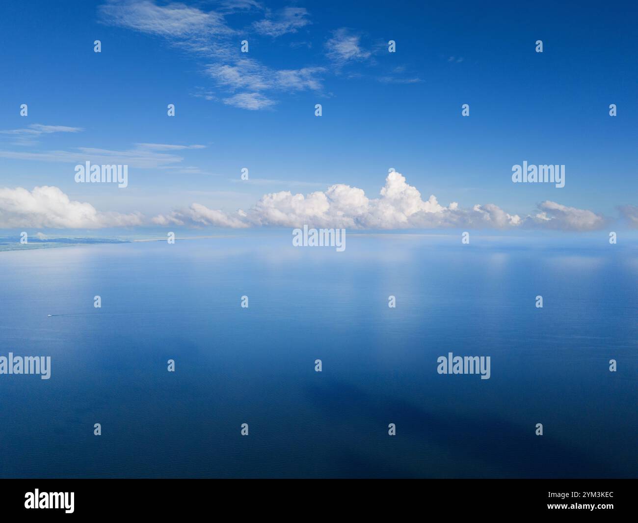 Expansive view of calm ocean waters reflecting vibrant blue sky dotted ...