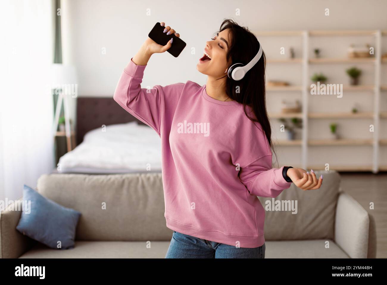 Young woman singing using smartphone as mic Stock Photo
