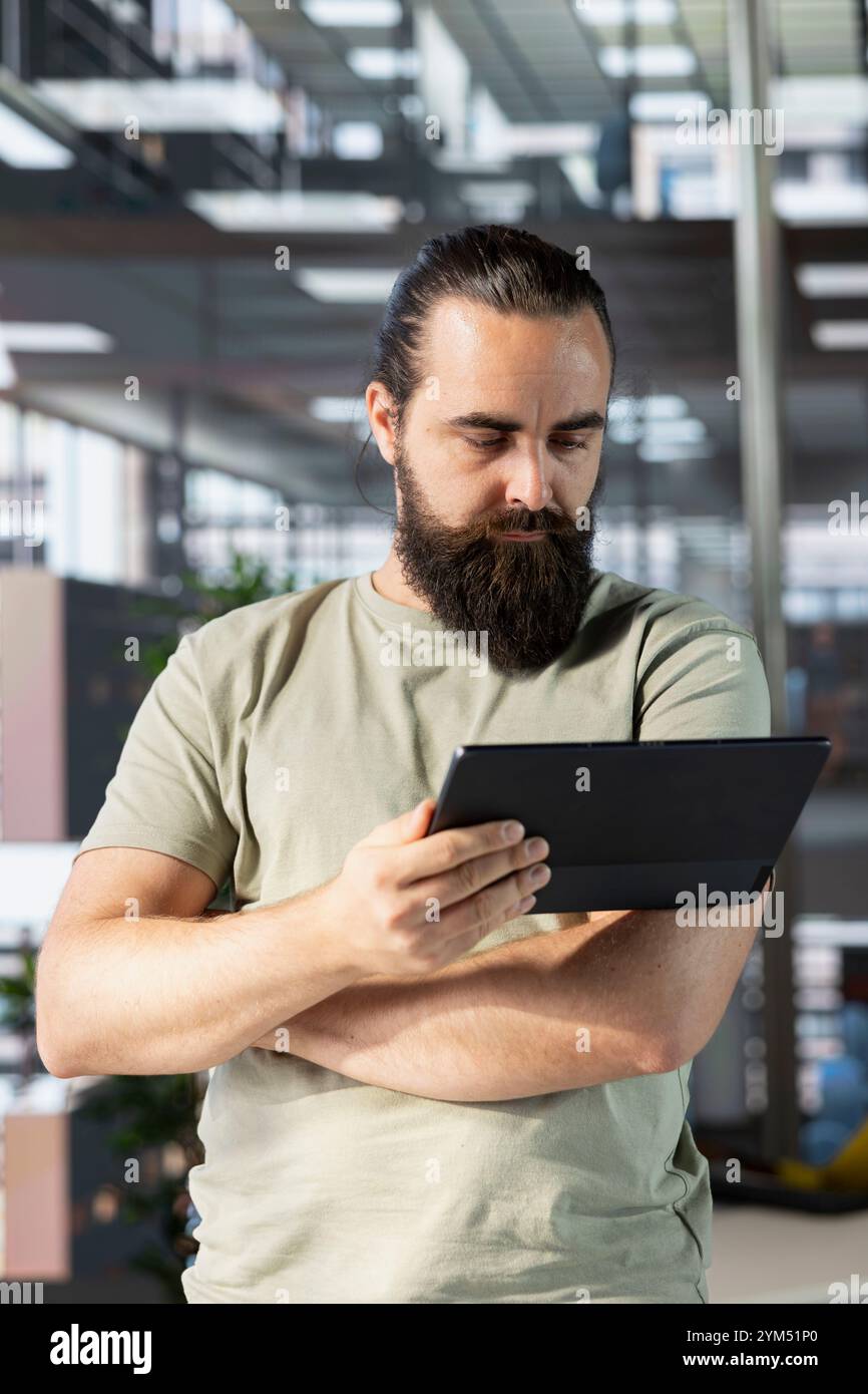 Programmer doing software debugging using tablet, checking errors in lines of code. Man working in office, fixing coding mistakes using device, looking for company security vulnerabilities Stock Photo