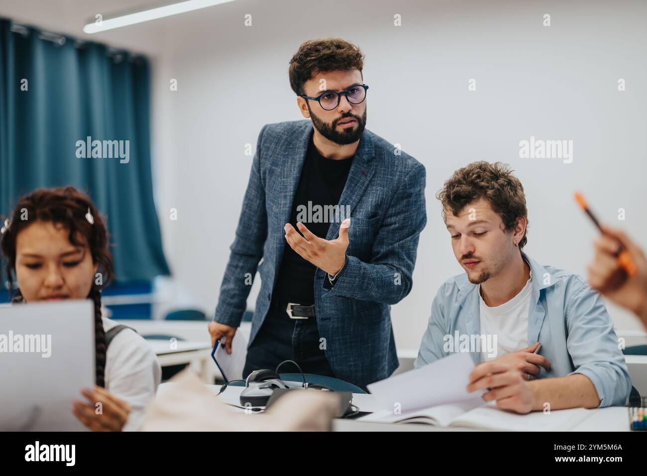 Professor assists students during an engaging classroom session Stock Photo