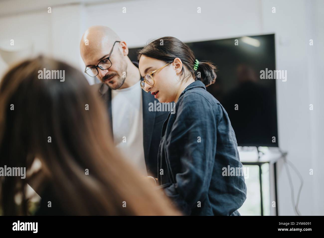 Students collaborating on project with professor in modern classroom setting Stock Photo