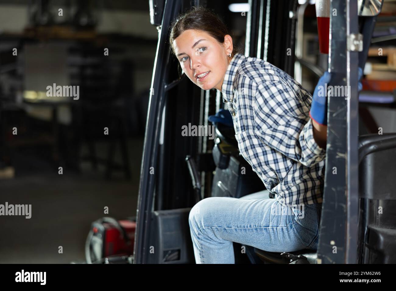 Young woman posing while sitting in forklift Stock Photo