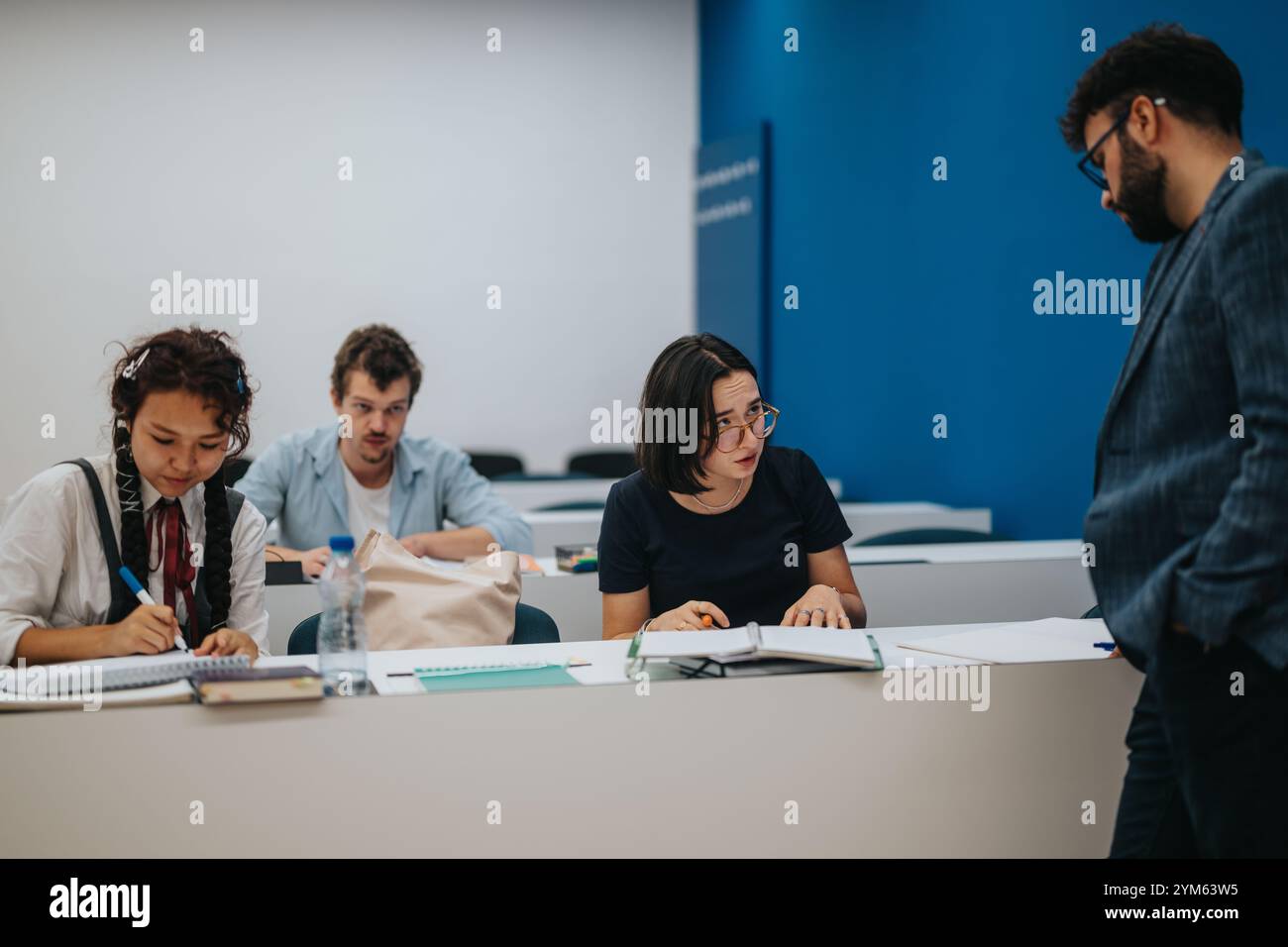 Professor assisting students during interactive classroom session Stock Photo