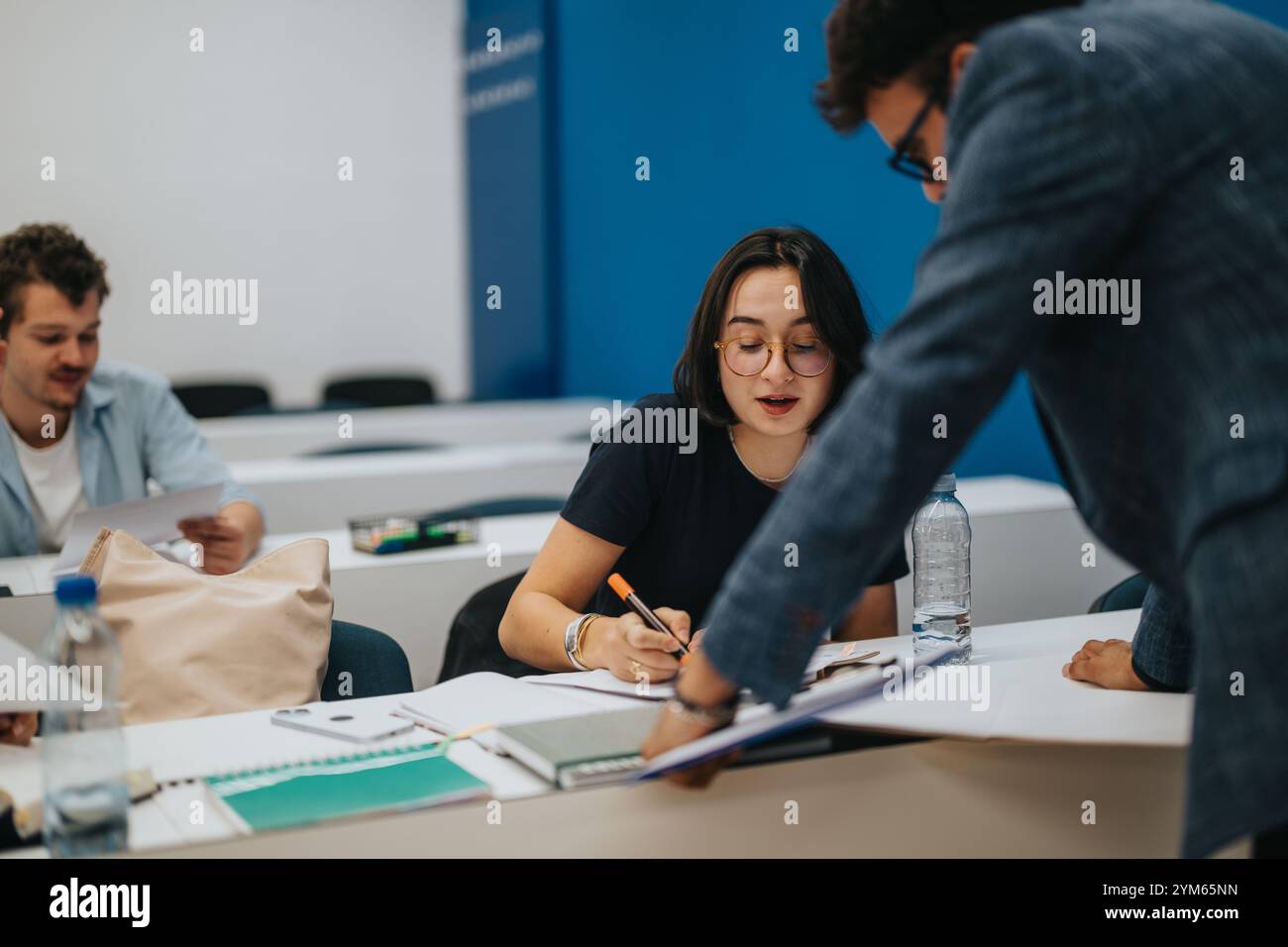 Professor assists students during classroom task in academic setting Stock Photo