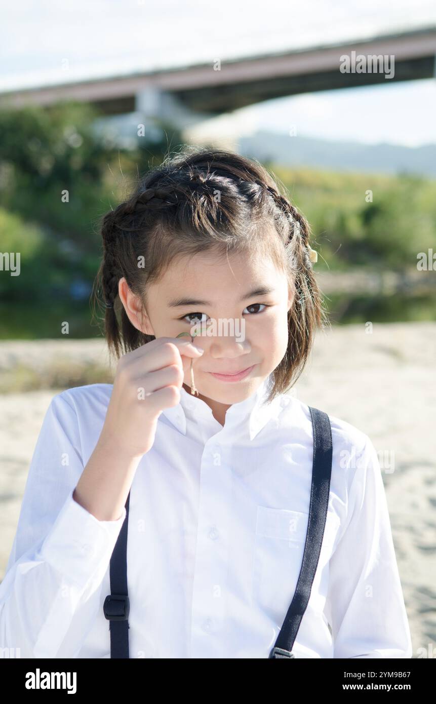 Primary school girl holding a twin leaf Stock Photo