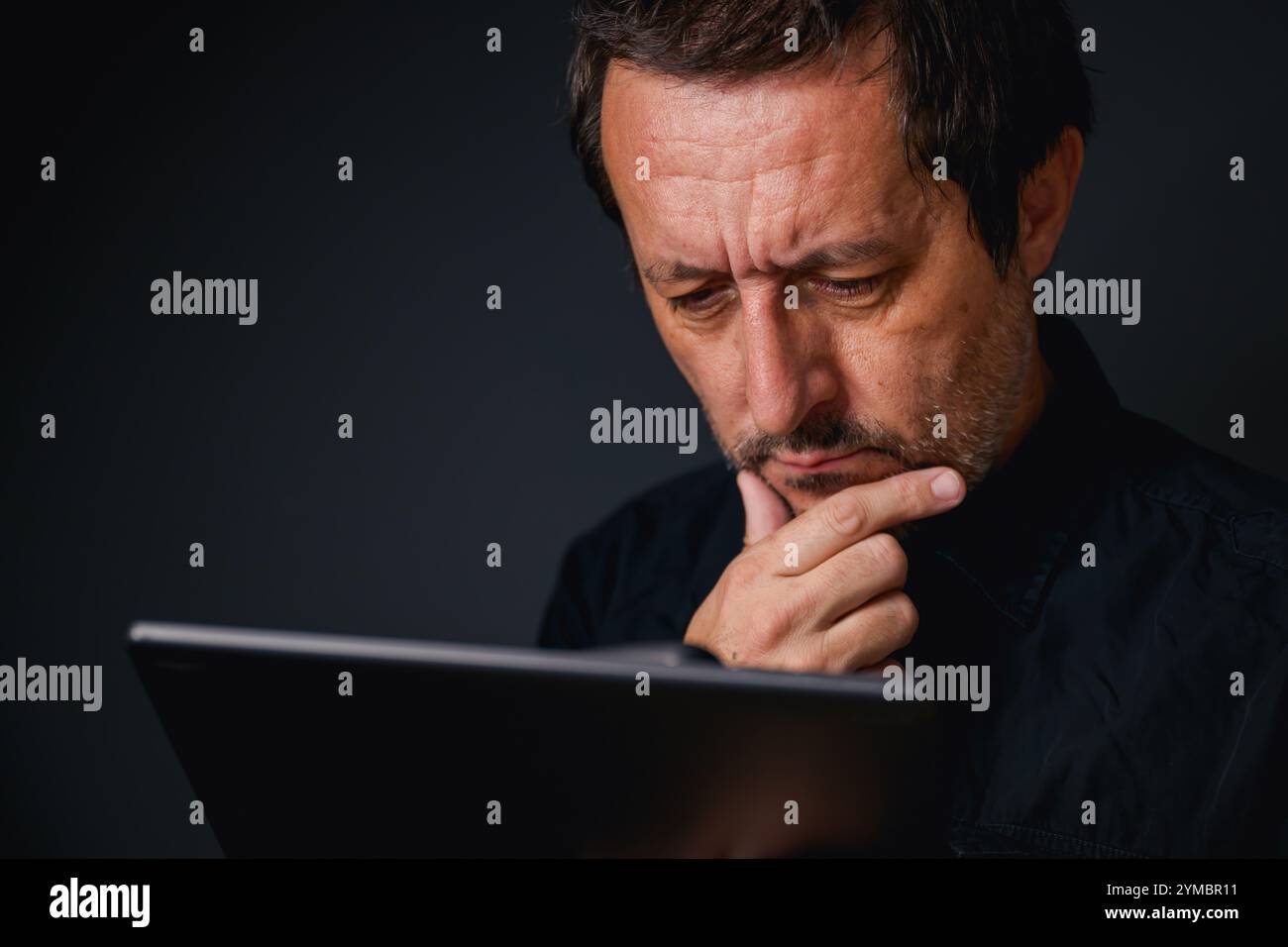 Man using digital tablet computer, low key with selective focus Stock Photo