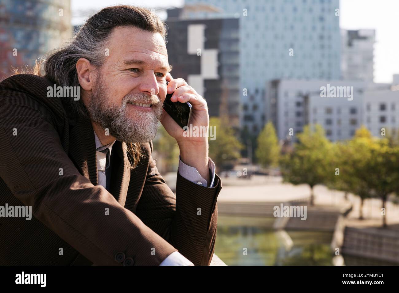 smiling middle age man with beard talking on phone Stock Photo