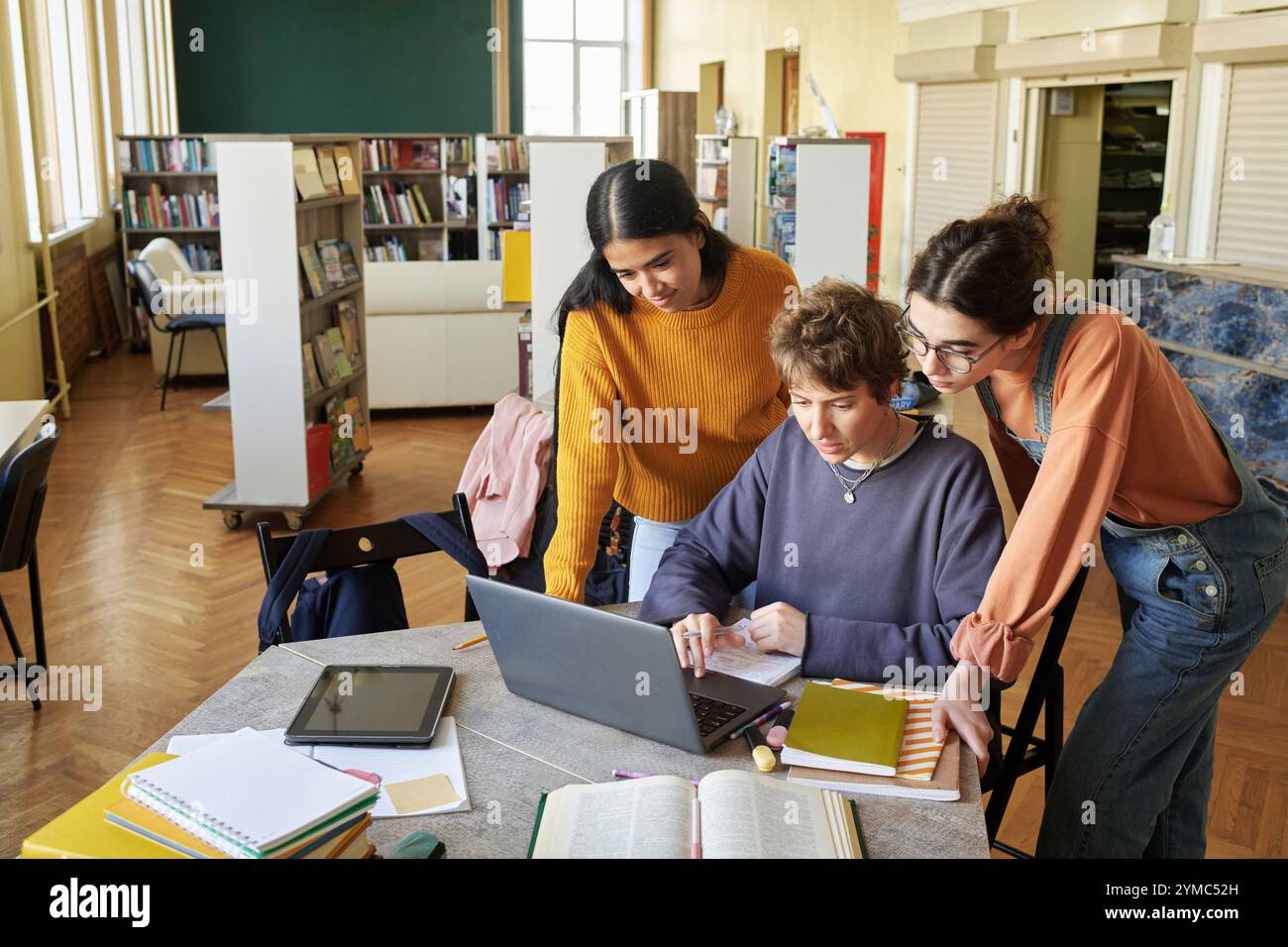Collaborating Students Working on Laptop in Library Stock Photo