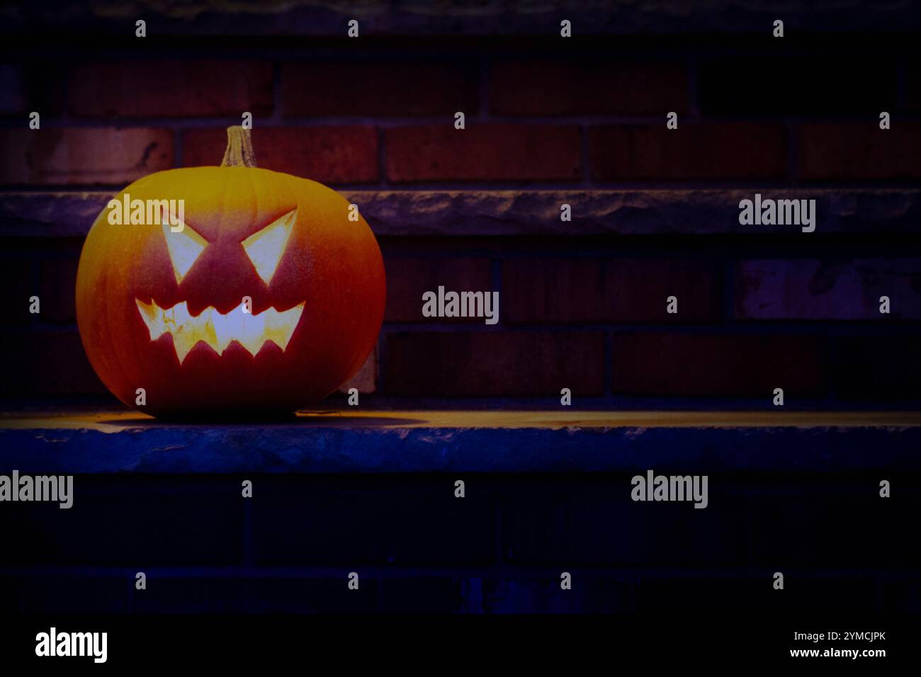 Illuminated Halloween jack-o-lantern on porch at night Stock Photo - Alamy