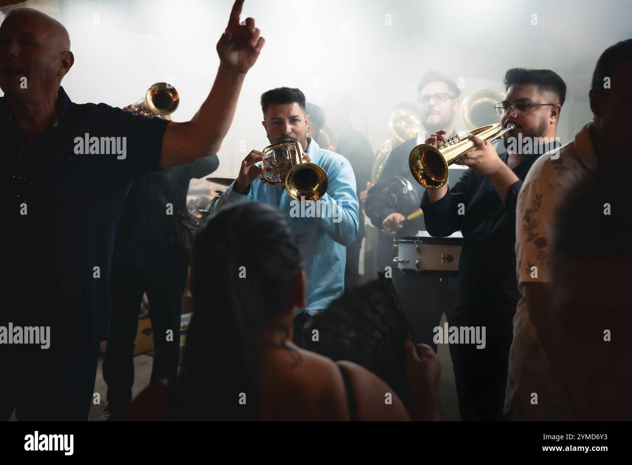 Guca, Serbia - 4 August 2024: Traditional brass orchestra playing and people dancing in smoke at Guca Trumpet Festival, traditional annual music event Stock Photo