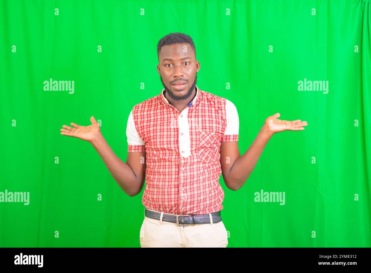 portrait of a handsome young man standing against a green background and holding empty spaces on his palms. Stock Photo