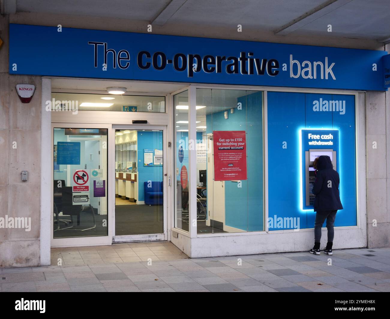 Co-operative Co-Op bank branch with a person outside using the external ATM machine. Plymouth, UK Stock Photo