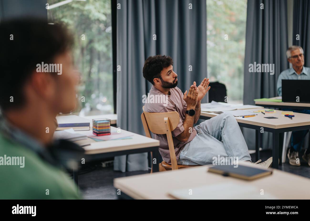 Students engaging with elderly professor in a modern classroom setting Stock Photo