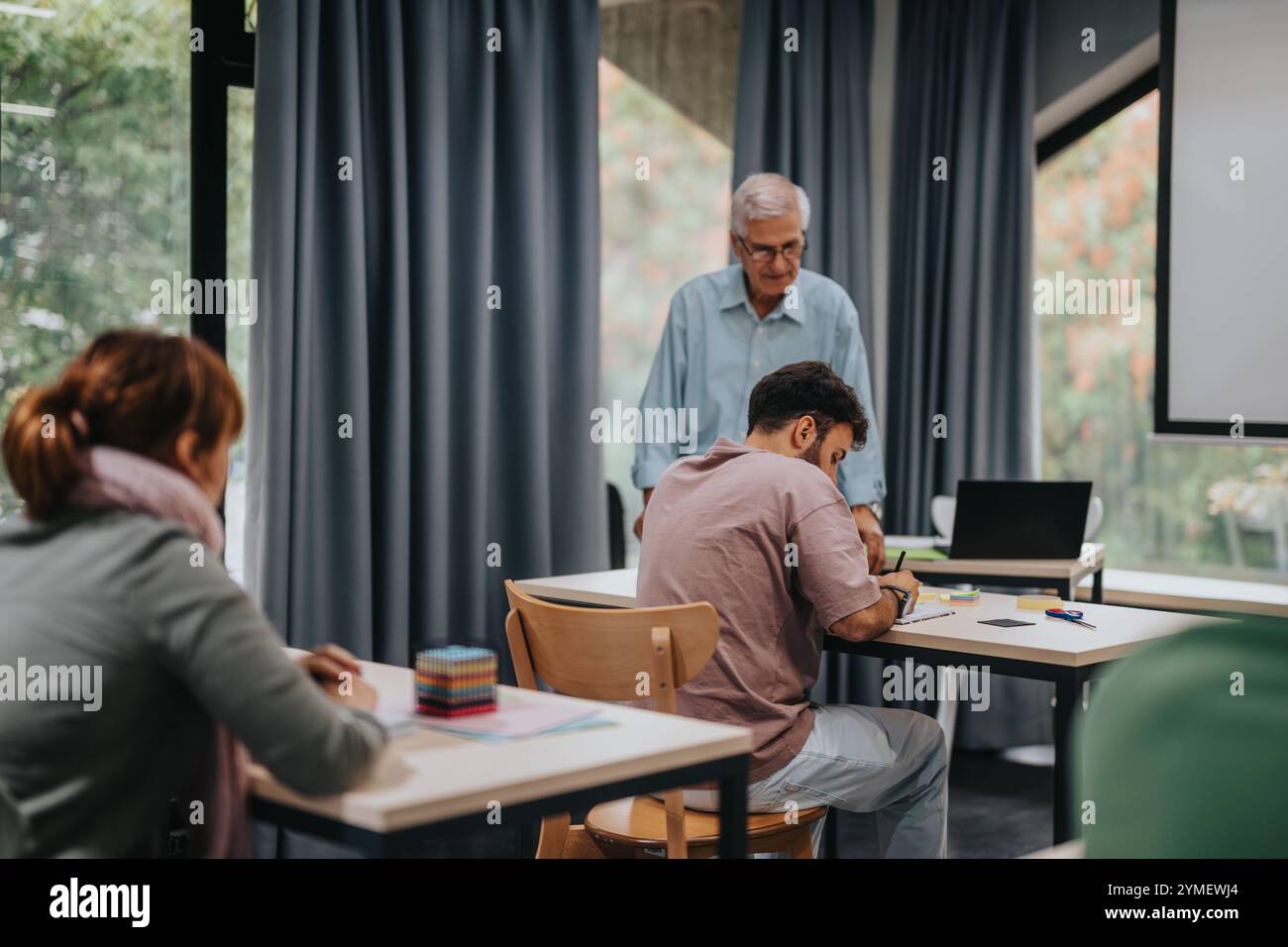 Students engaged in a classroom setting with elderly professor Stock Photo