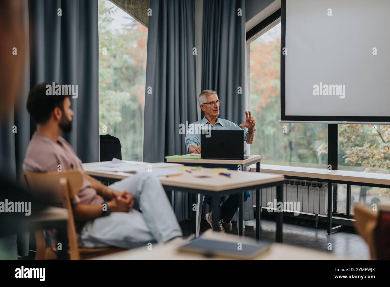 Students engaging with elderly professor in modern classroom setting Stock Photo