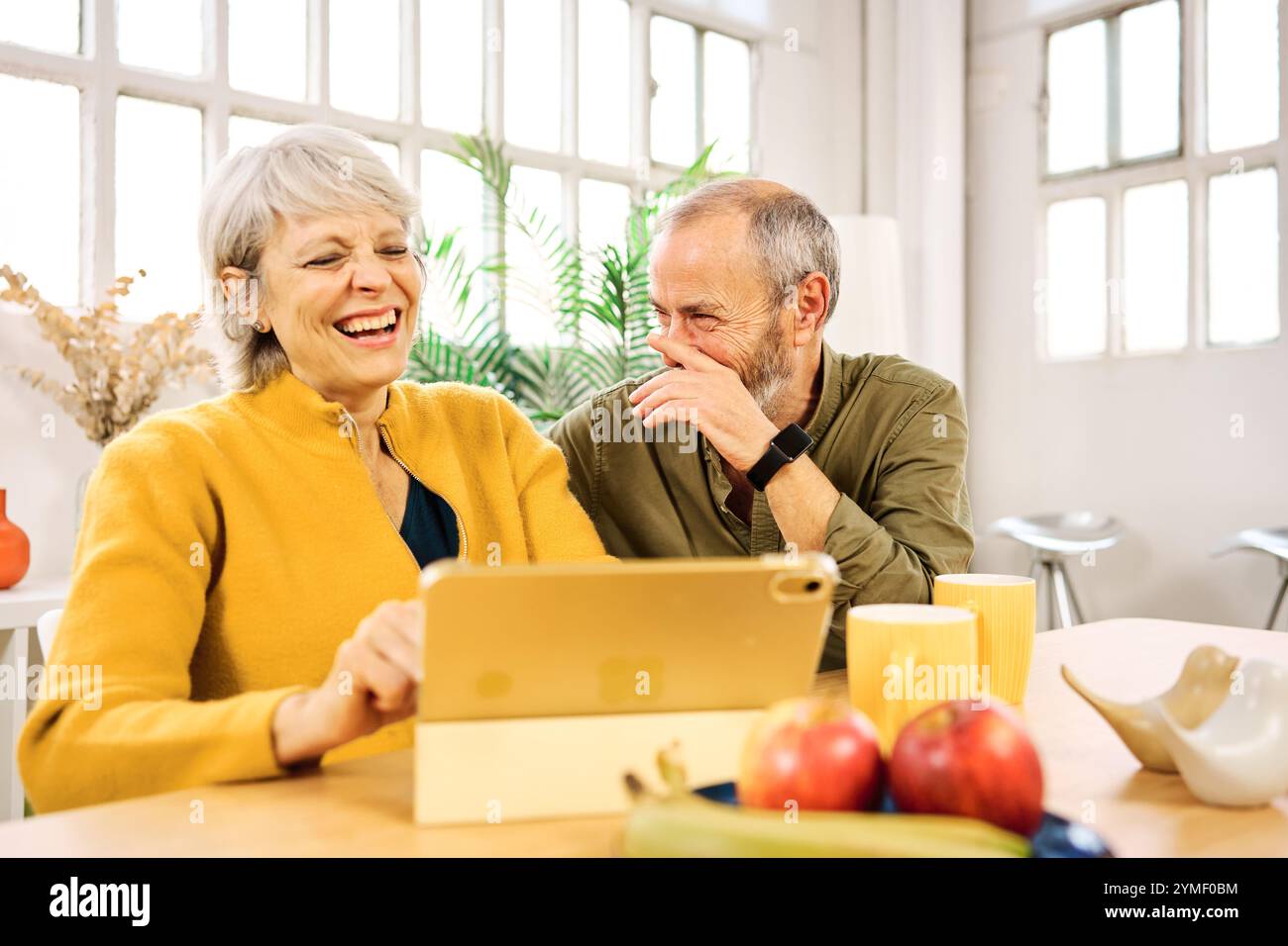 Senior couple laughing while using digital tablet at home Stock Photo