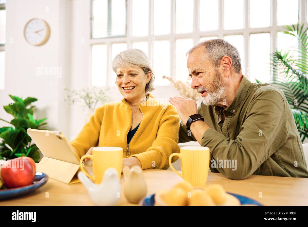 Senior couple using digital tablet at home having breakfast Stock Photo