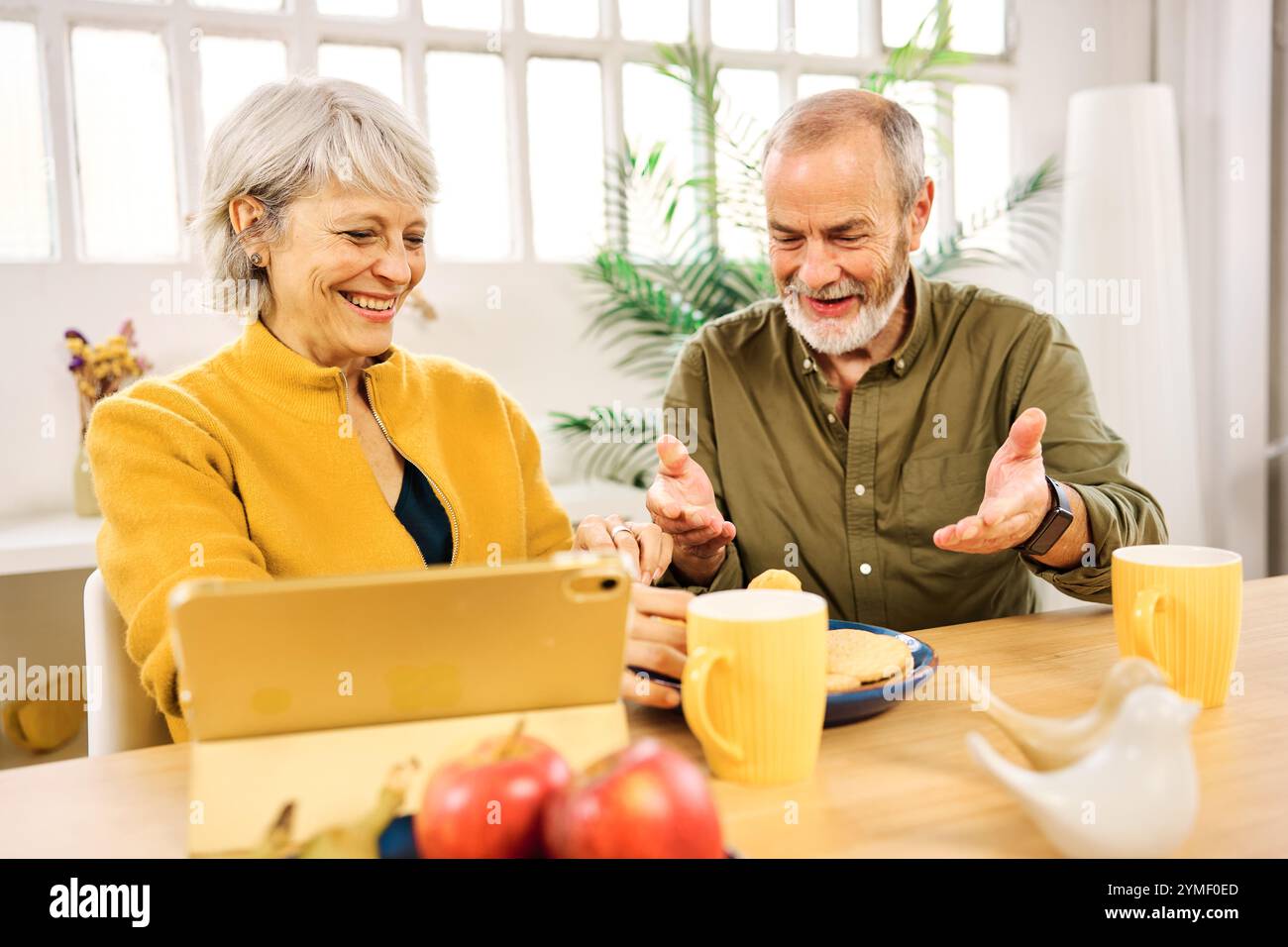Senior couple having breakfast and using tablet at home Stock Photo