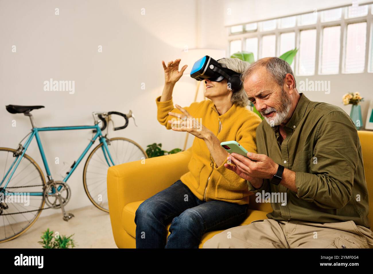 Senior couple exploring virtual reality and using smartphone at home Stock Photo
