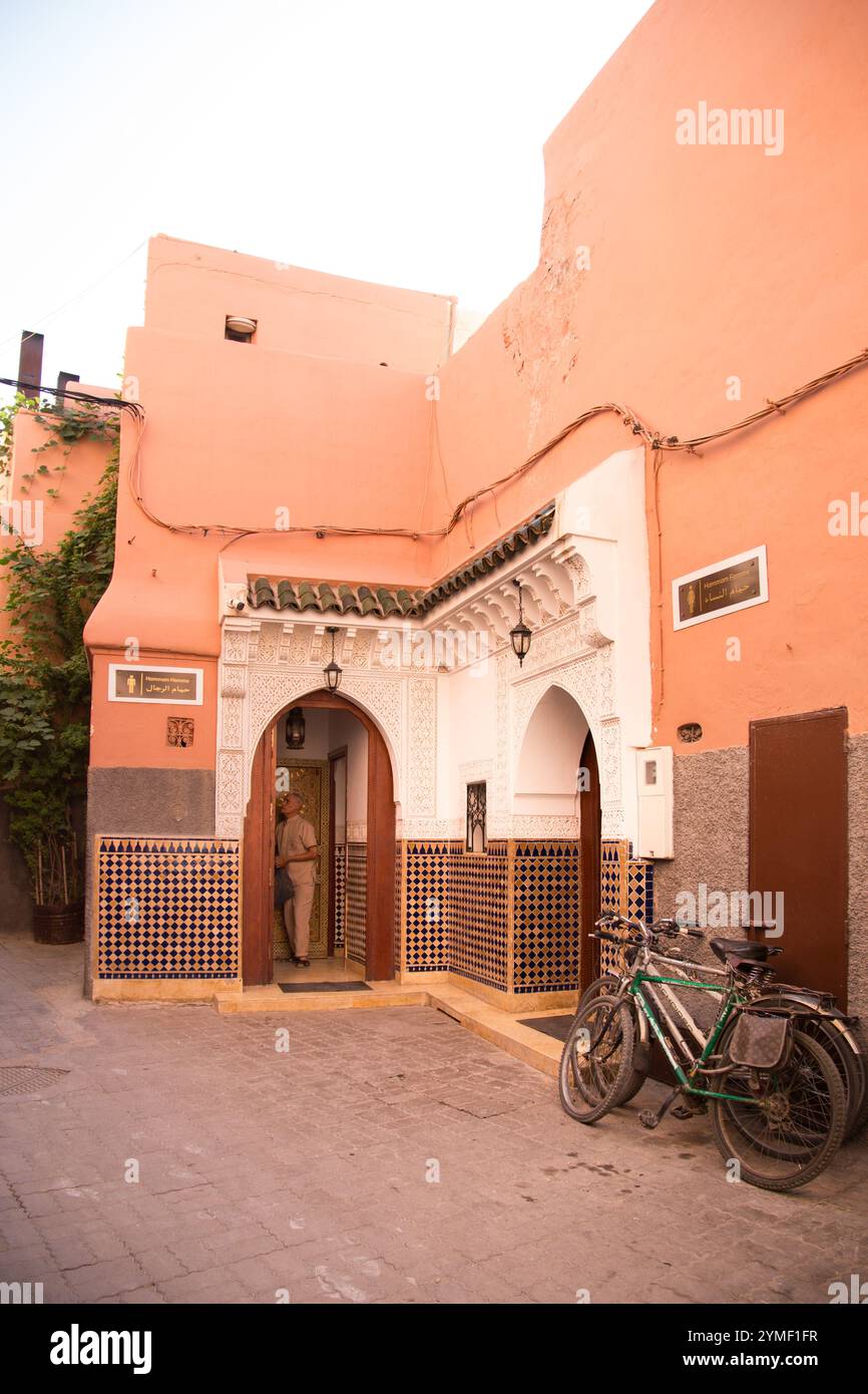 Traditional Moroccan doorway to Men's Hamam with ornate tiles and carved arch in Marrakesh medina, with bicycles leaning nearby. Stock Photo