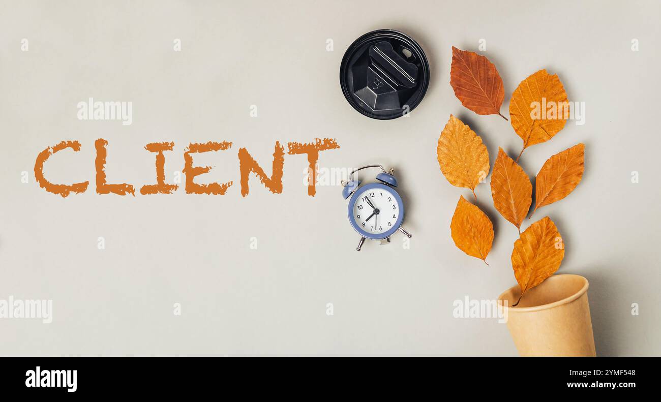 Clock and a cup are placed on a table with the word client written in ...