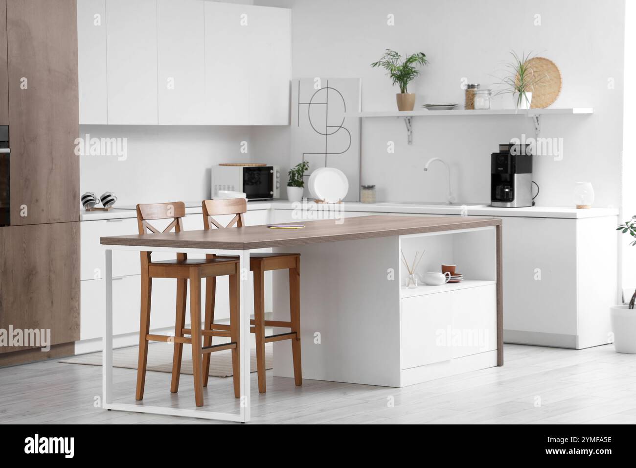 Interior of light kitchen with modern island table and white counters ...