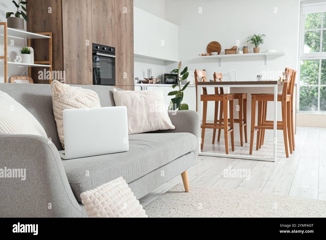 Interior of light kitchen with counters and laptop on sofa Stock Photo ...