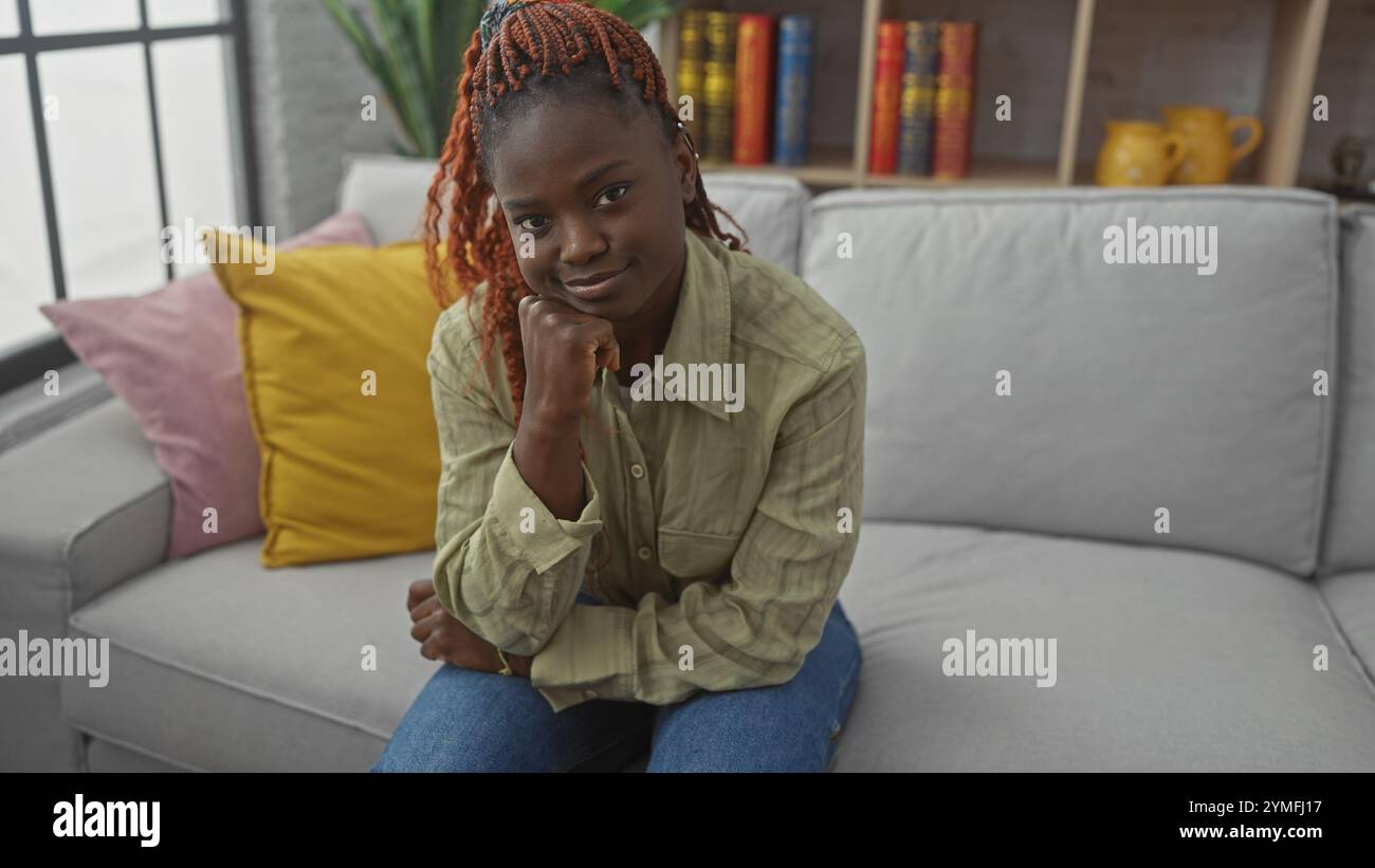 A thoughtful young african woman relaxing in her modern living room ...