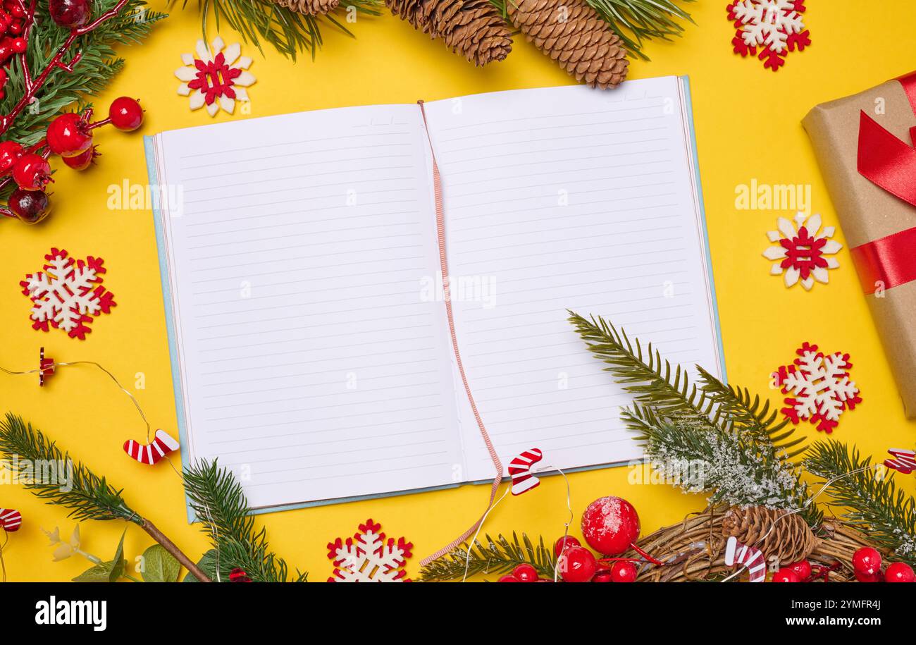 Open notebook with empty blank sheets on yellow background with Christmas decor, top view Stock Photo