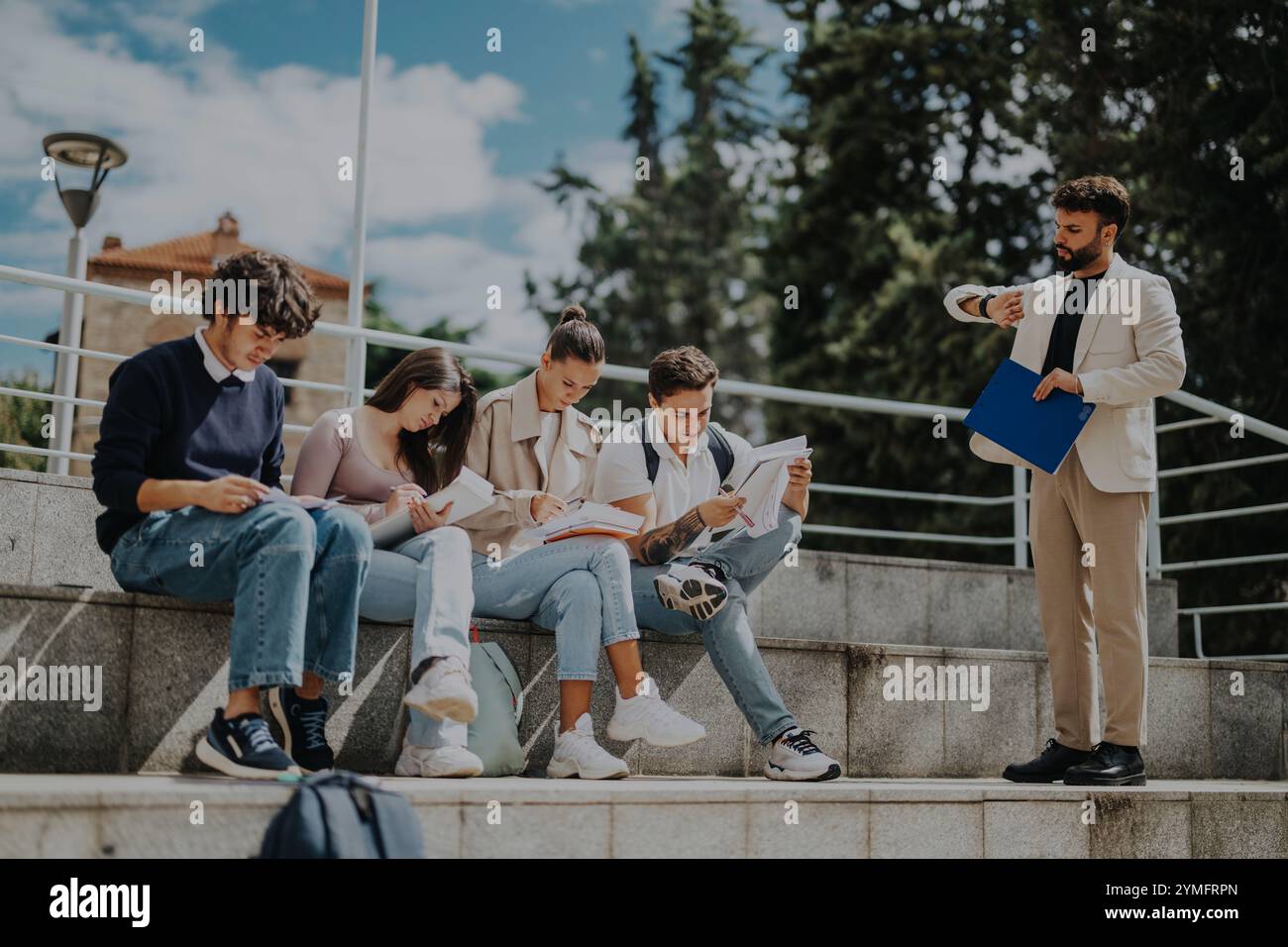 High school students collaborating outdoors with professor's guidance Stock Photo