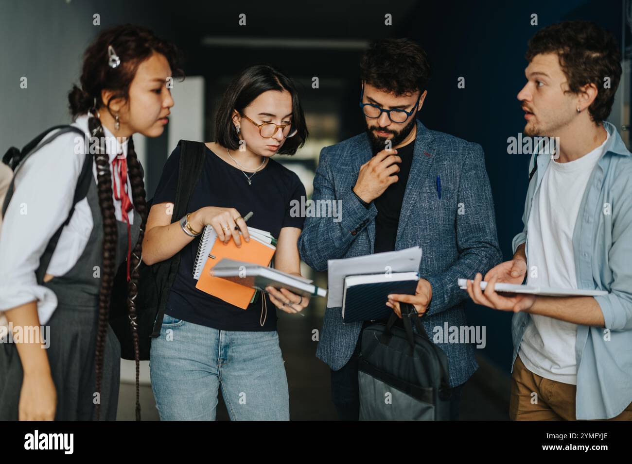 Students engaging in thoughtful discussion with professor between classes Stock Photo